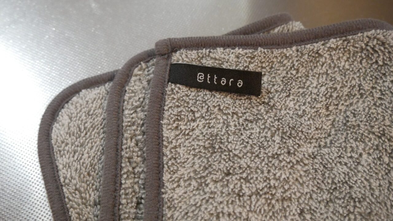 アッタラの油汚れクロス。グレーの生地で、縁のパイピングと吊り下げ収納ができるループ付きデザイン。