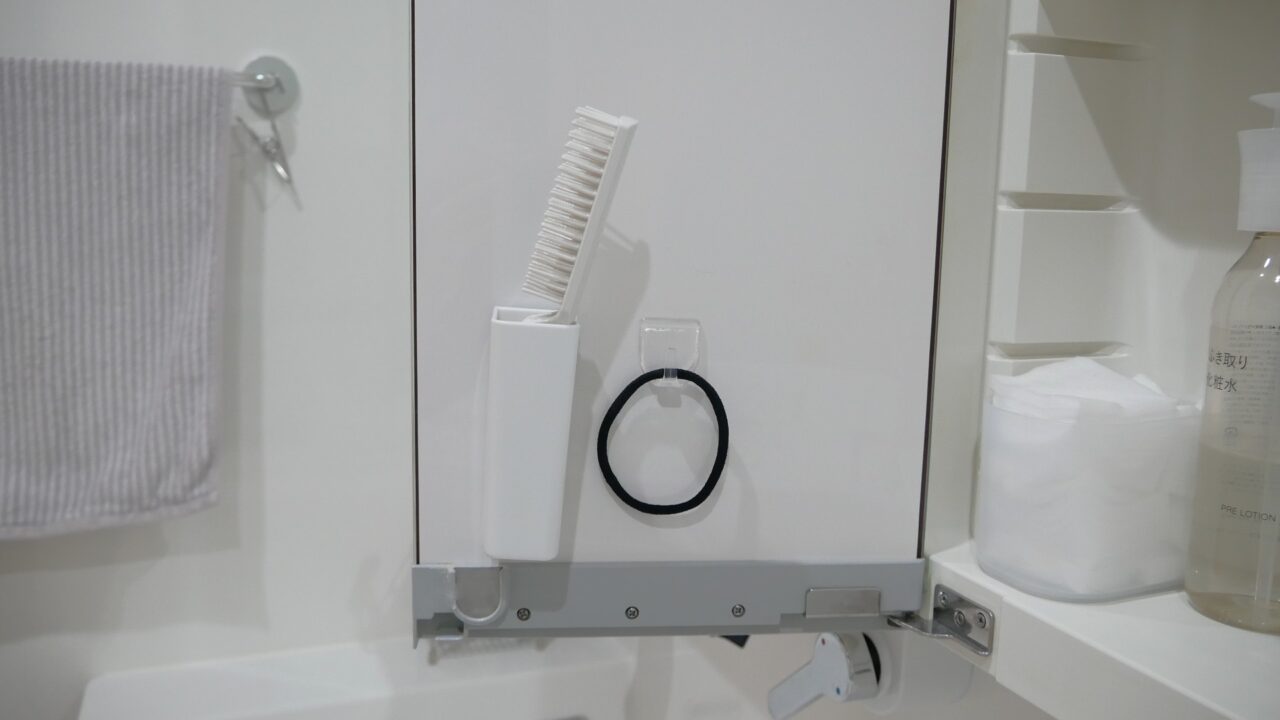 鏡裏収納の扉裏に取り付けたフックに、ヘアゴムをかけている様子。