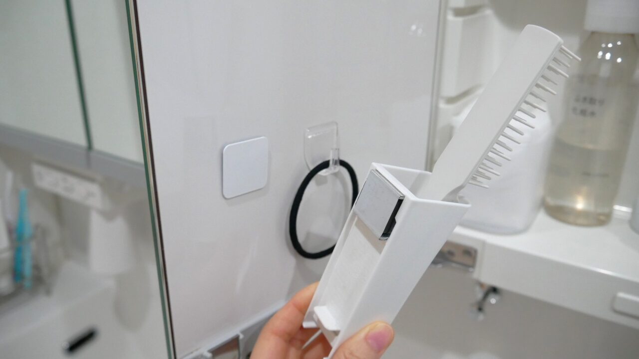 鏡裏収納の扉裏に、百均のマグネット用取り付けパネルとマグネットポケットを使ってヘアブラシを入れている様子。