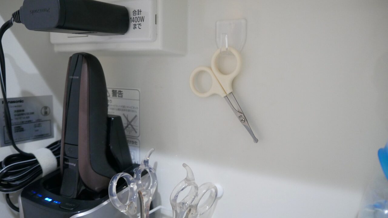 小さなケア用はさみを、鏡裏収納の壁面に取り付けたフックにかけている様子。