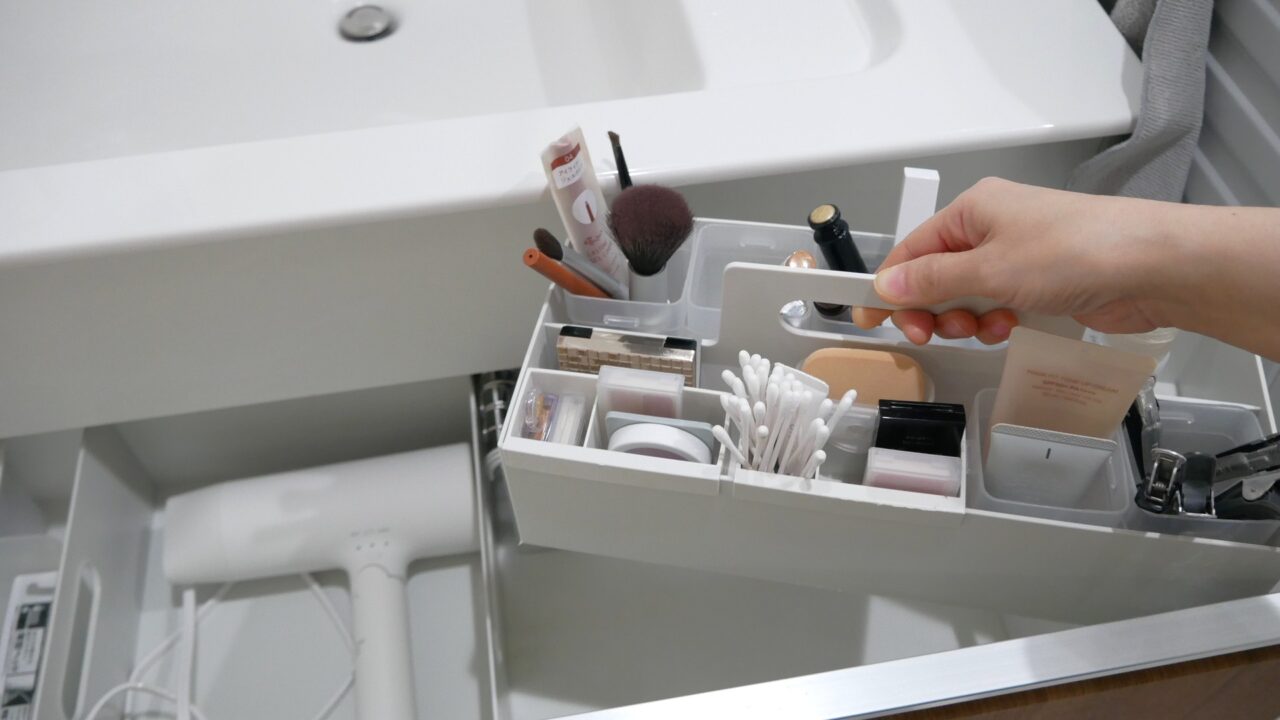洗面台下の引き出しから、キャリーボックスにまとめたメイクグッズを持ち上げている様子。