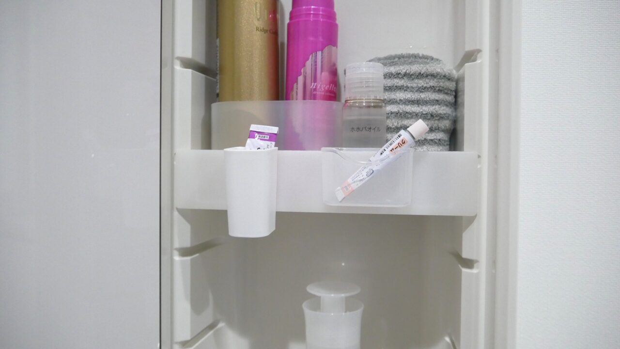 鏡裏収納の棚にひっかけた百均ケースに、小さいチューブが入っている様子。